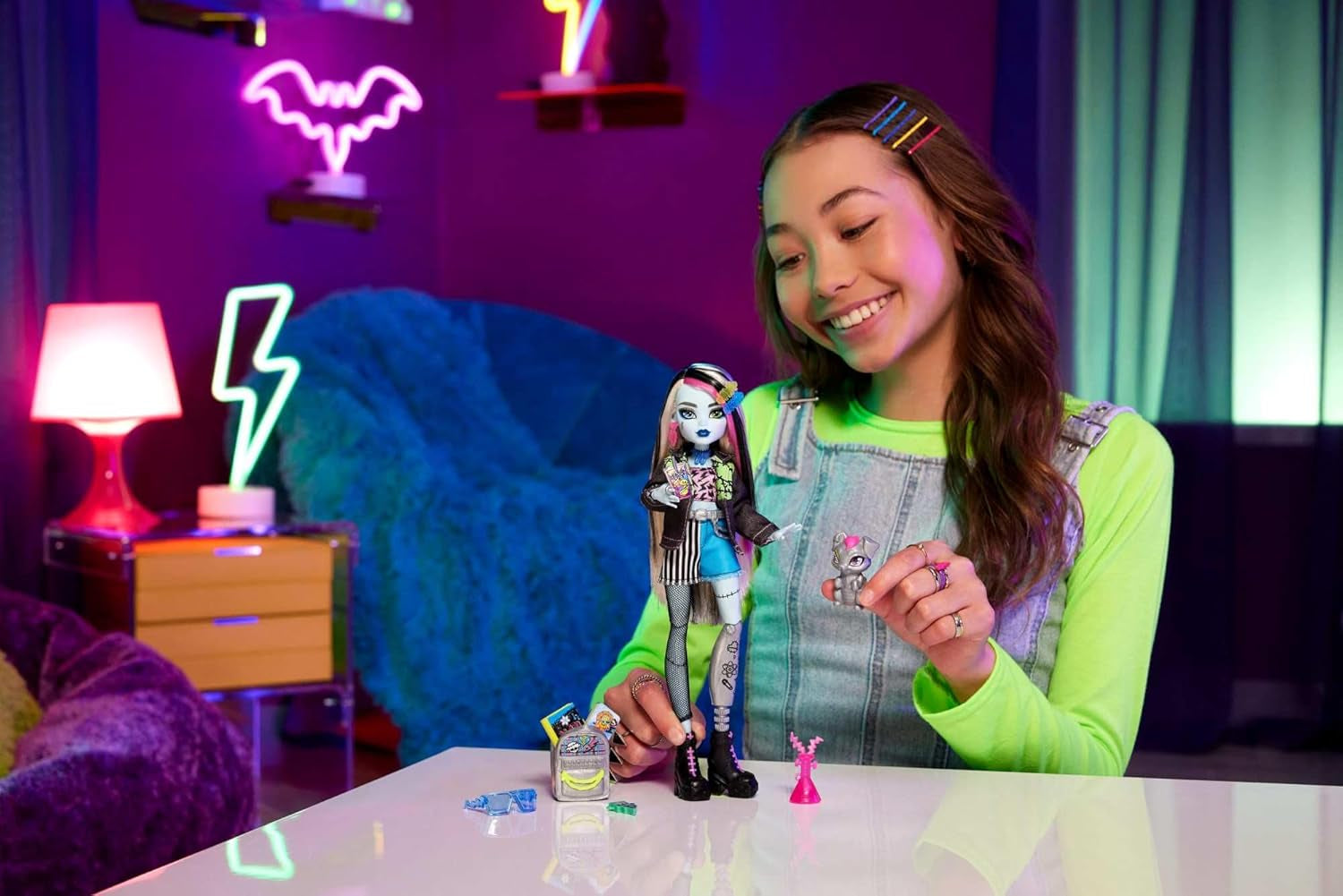Păpușa Monster High Frankie Stein în jachetă de blugi și pantaloni scurți, include și cățelușa ei Watzie și accesorii precum un rucsac, o gustare și un caiet, HXH73